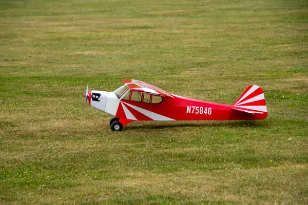 Rood-wit modelvliegtuig op de grasbaan