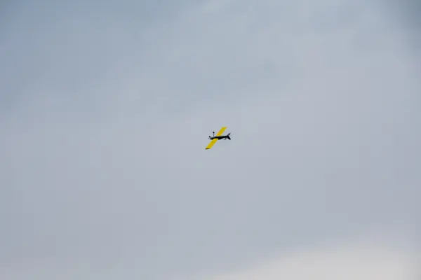 Geel modelvliegtuig in de vlucht